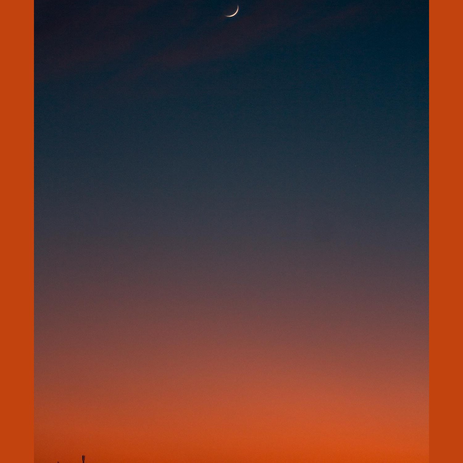 Crescent moon and fiery orange sunset horizon